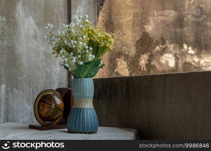 Bouquet of flowers in Blue handmade ceramic vase and globe on white textured table cloth with old cement wall at the balcony house. Home decor, Selective focus.
