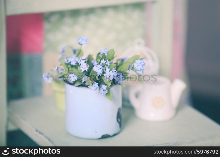 Bouquet of forget-me-not in a blue cup on a wooden windowsill. Forget-me-not in rustic cup