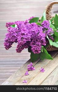bouquet of fresh lilac flowers in a basket put on a wooden garden table