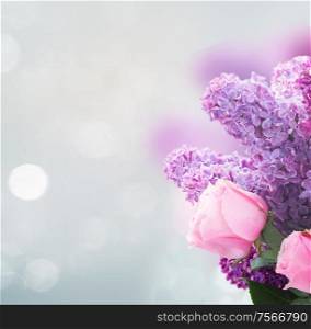 Bouquet of fresh purple Lilac flowers with pink roses over gray bokeh background with copy space. Lilac flowers with roses