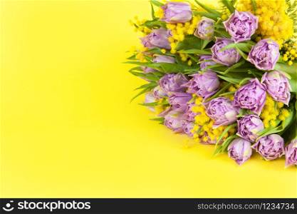 Bouquet of lilac tulips and yellow mimosas on yellow background, copy space, side view, closeup. March 8, February 14, birthday, Valentine?s, Mother?s, Women?s day celebration, spring concept.