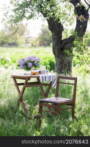 bouquet of lilacs on the table in the summer garden. garden furniture - table and chair. still life