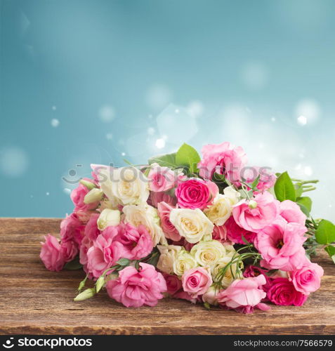 bouquet of pink and white fresh roses and eustoma on wood with blue background. bouquet of fresh roses