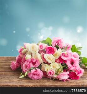 bouquet of pink and white fresh roses and eustoma on wood with blue background. bouquet of fresh roses