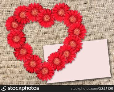 Bouquet of red flowers as heart-form with message-card on textile background. Close-up. Studio photography.