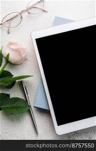 Bouquet of roses and tablet  on concrete background. Top view.