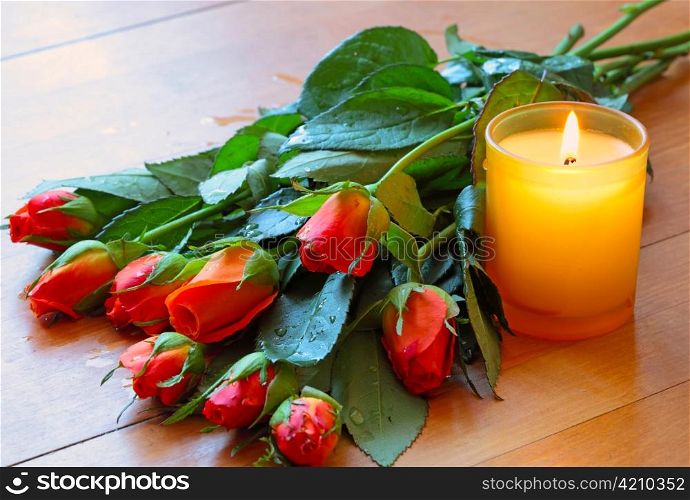 Bouquet of roses, candle on table made of wood