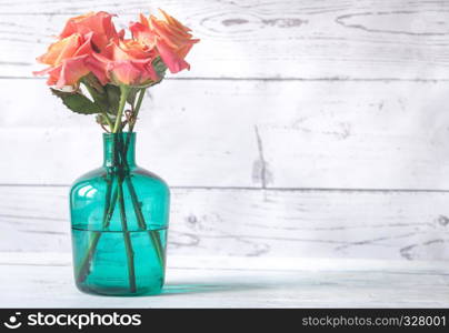 Bouquet of roses in the vase on the wooden background