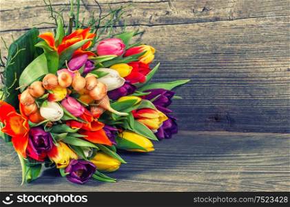 Bouquet of spring tulip flowers on wooden background. Vintage style toned picture