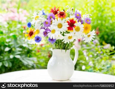 bouquet of summer flowers in a jar on green background