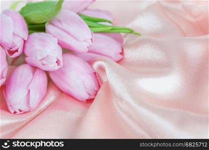 Bouquet of tulip flowers on a background of silk fabric; with copy-space