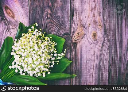 bouquet of white lilies of the valley on a gray cracked wooden surface, empty space on the right