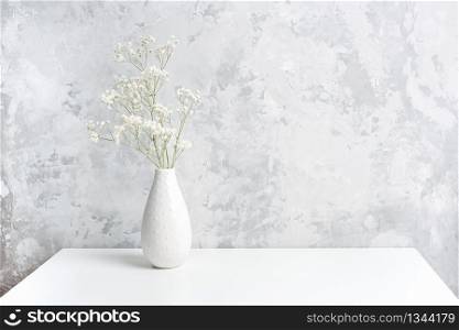 Bouquet of white small delicate flowers gypsophila in vase on table agains gray stone wall. Copy space Minimal style. Template for postcard, text, design Concept Women&rsquo;s day, Mothers Day.. Bouquet of white small delicate flowers gypsophila in vase on table agains gray stone wall. Copy space Minimal style. Template for postcard, text, design Concept Women&rsquo;s day, Mothers Day