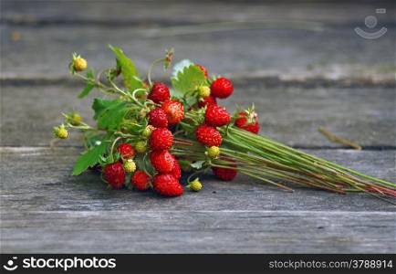 Bouquet of wild strawberry with berries on wooden table