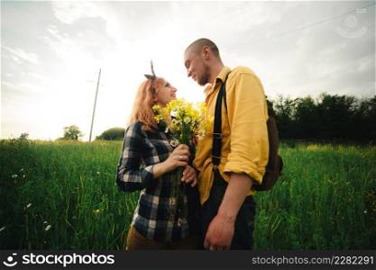 bouquet of wildflowers in woman&rsquo;s hand. Loving hipster couple walking in the field, kissing and holding hands, hugging, lying in the grass in the summer at sunset. valentines day.. bouquet of wildflowers in woman&rsquo;s hand. Loving hipster couple walking in the field, kissing and holding hands, hugging, lying in the grass in the summer at sunset. valentines day