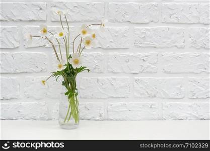 Bouquetof white wildflowers in vase on table background white brick wall Copy space Minimal style. Template for postcard, text, design Concept Women&rsquo;s day, Mothers Day, Hello summer or Hello spring.. Bouquetof white wildflowers in vase on table background white brick wall Copy space Minimal style. Template for postcard, text, design Concept Women&rsquo;s day, Mothers Day, Hello summer or Hello spring