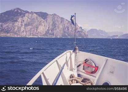 Bow of a boat on a boat tour. Blue water and mountain range, Lago di Garda, Italy