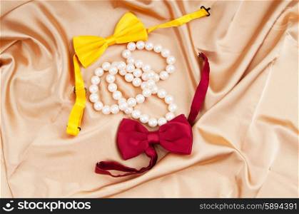 Bow ties and pearl necklace on the satin