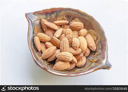 Bowl full of almonds on white with shadow