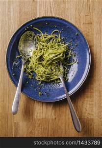 Bowl of basil pesto and pasta on an old wood table.