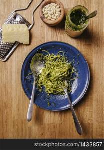 Bowl of basil pesto and pasta on an old wood table.