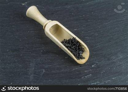 Bowl of black charcoal sea salt, in wooden scoop or macro, background