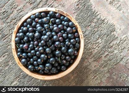 Bowl of blackcurrant on the wooden board