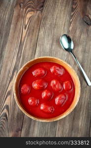 Bowl of canned tomatoes on the wooden background