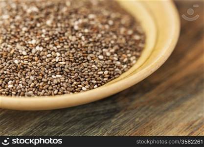 bowl of chia seeds on wood surface - a close-up with a shallow depth of field