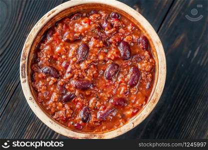 Bowl of chili con carne on a wooden table: top view