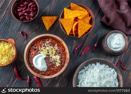 Bowl of chili con carne with toppings on a wooden table