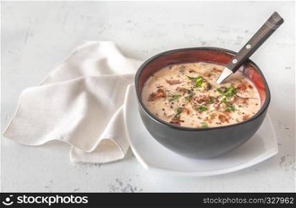 Bowl of clam chowder garnished with chopped bacon and fresh parsley