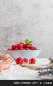 Bowl of delicious fresh ripe raspberries on table, closeup view