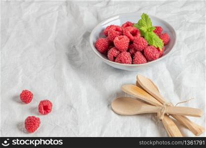 Bowl of delicious fresh ripe raspberries on table, closeup view