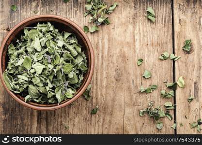Bowl of dried oregano leaves on wooden background. Dried oregano herb