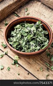 Bowl of dried oregano leaves on wooden background.Dried oregano seasoning. Dried oregano herb