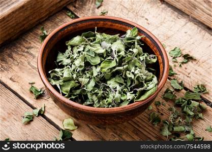 Bowl of dried oregano leaves on wooden background.Oregano or marjoram leaves. Dried oregano herb