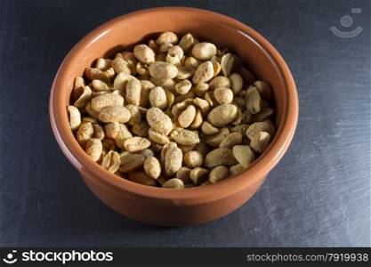 Bowl of dry roast peanuts on slate mat.