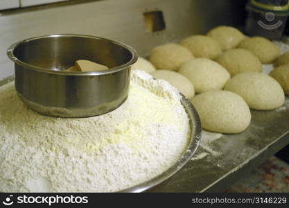 Bowl of flour and bread rolls of trays