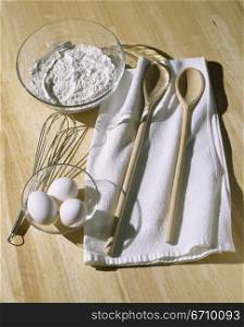 Bowl of flour near a whisk and eggs