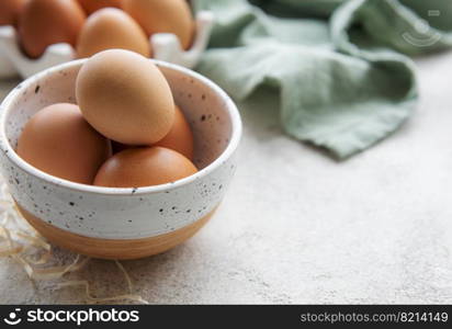 Bowl of fresh  brown eggs on concrete background