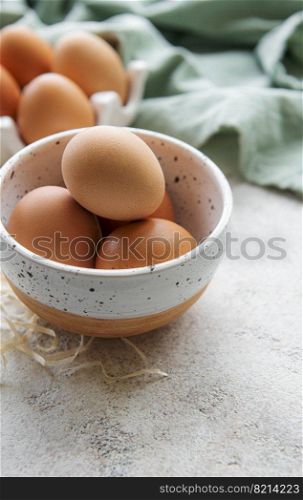 Bowl of fresh  brown eggs on concrete background