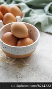 Bowl of fresh  brown eggs on concrete background