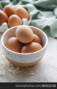 Bowl of fresh  brown eggs on concrete background