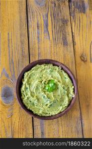 Bowl of fresh guacamole on rustic background