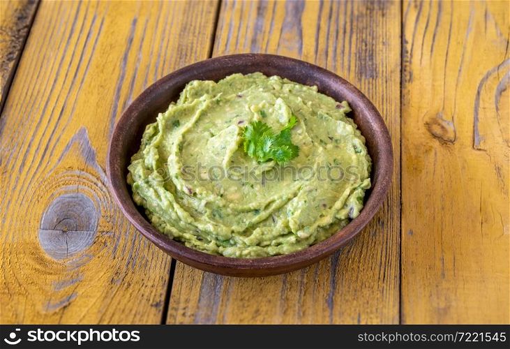 Bowl of fresh guacamole on rustic background