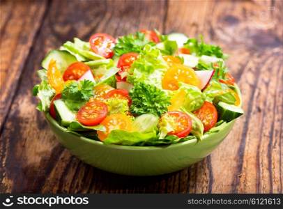 bowl of fresh salad with vegetables on wooden table