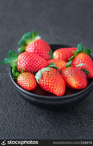 Bowl of fresh strawberries on the wooden table