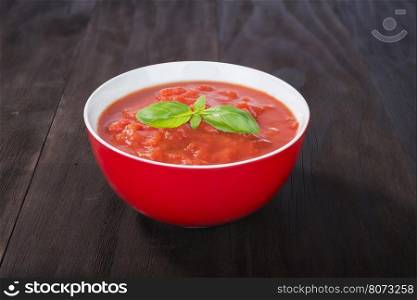 bowl of fresh tomato soup on old wooden background