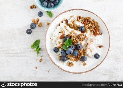 Bowl of granola with fresh blueberry, cottage cheese or curd, yogurt and nuts. Healthy food. Breakfast. Top view